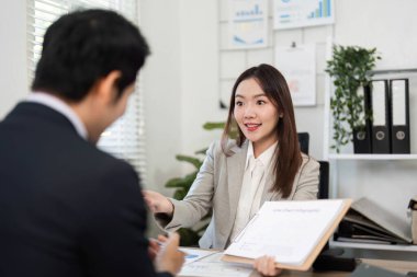 Müşteri ve mali danışman, finansal stratejiler ve güçlendirme için gelecekteki planlara odaklanarak, parlak bir ofiste görüşlerini paylaşırlar..