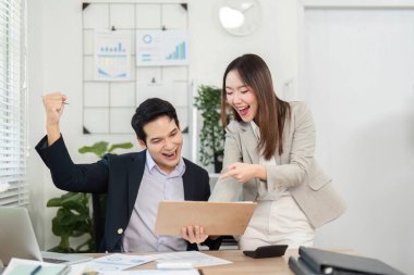 Finansal verileri neşeyle inceleyen iki profesyonel, canlı bir çalışma alanında takım çalışması ve başarı sergiliyor..