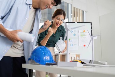 Modern bir çalışma alanında modelleri ve yenilenebilir enerji çözümlerini hevesle inceleyen iki profesyonel.