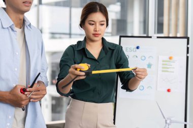 Sürdürülebilir bir inşaat projesi için boyutları ölçen bir mühendis, modern bir çalışma alanında elleriyle yapılan işbirliğini gösteriyor.