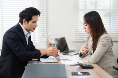 Bir müşteri, profesyonel bir çevredeki yatırım stratejilerine odaklanan mali belgeleri danışmanıyla dikkatle gözden geçirir.