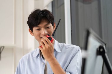 Genç bir mühendis telsiz aracılığıyla iletişim kurarak modern bir inşaat ortamında sorunsuz proje koordinasyonunu sağlıyor..