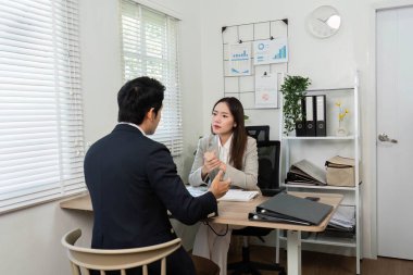 Modern bir ofiste, iki iş adamı bir finansal danışmanlık yapar, stratejileri tartışır ve analiz için bir hesap makinesi kullanır..