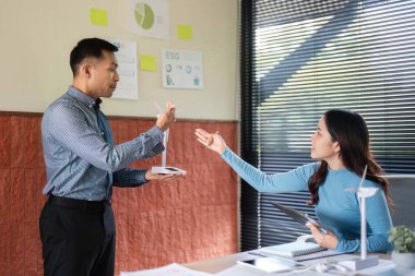 Profesyoneller bir rüzgar türbini modelini analiz ederken ve görüşleri paylaşırken ESG girişimleri üzerine odaklanmış bir tartışma gerçekleşiyor.