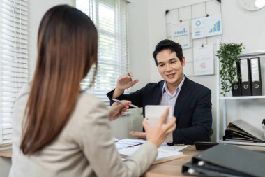 Profesyonel bir ortamda bir erkek ve kadın finansal stratejileri tartışıyor, işbirliği ve takım çalışmasını vurguluyor.