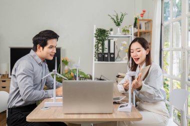 Modelleri kullanarak ESG girişimlerini ve yenilenebilir enerji stratejilerini tartışan iş adamları arasında odaklı bir toplantı.