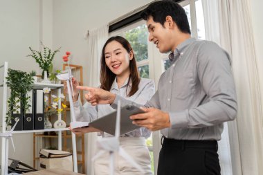 İki profesyonel, işbirlikçi bir çalışma alanında ESG ilkelerine odaklanarak yenilenebilir enerji prototiplerini analiz ediyor.