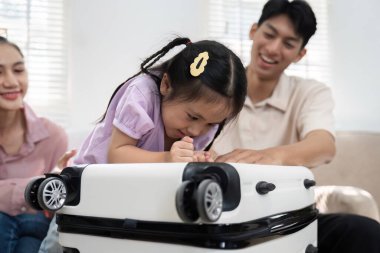 Genç bir kız, anne ve babası ona destek olurken, bir bavulu keşfederek vakit geçirmekten zevk alıyor. Neşeli bir aile ortamını yansıtıyor..