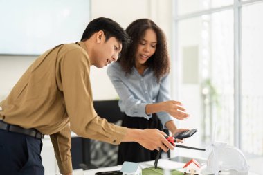 İkili aktif olarak sürdürülebilir yapı uygulamalarında işbirliği yapıyor, modeller ve malzemeler birlikte beyin fırtınası yaparken masaya yayılıyor..