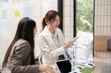 İki kadın sürdürülebilir iş stratejileri hakkında verimli bir tartışmaya girişiyor. Yeşillik dolu modern bir ofiste planlar ve fikirler gözden geçiriliyor..