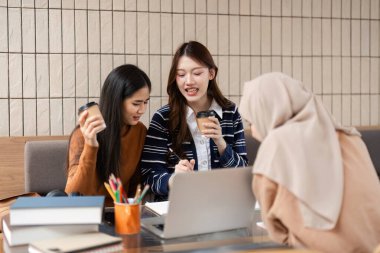 Sıcak, modern bir kafede, üç arkadaş kahkahalarla ve fikirlerle kahkahalarla birbirlerini destekliyor, kahkahalarla kahkahalarla kahve içerek, işbirliğinin ve öğrenmenin keyfini vurguluyorlar..