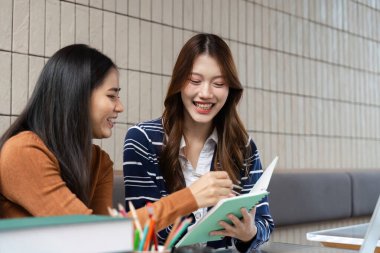 Canlı bir kafede, iki öğrenci ortak bir projeye, fikirlerini paylaşıp notlar yazarak arkadaşlıklarını ilerletmeye çalışıyorlar..