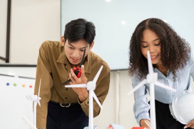 Rüzgar enerjisi modelleriyle çalışırken bulgularını ve stratejilerini tartışan iki profesyonel arasındaki odaklı işbirliği.