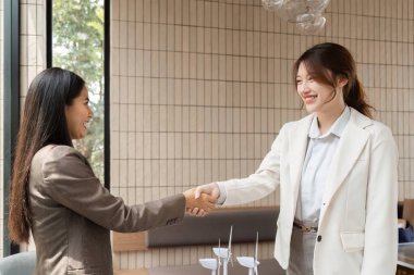 Aydınlık bir ofis ortamında, iki kadın profesyonel el sıkışarak sürdürülebilir ve yenilenebilir enerji çözümlerine yönelik taahhütleri teşvik ederek anlaşmayı tamamladı.