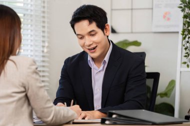 Bir işadamı notlar yazarken gülümsüyor, mali stratejiler hakkında verimli bir tartışma yapıyor..