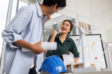 Mühendisler, modern ofis ortamında başarılı projelerini tartışırken heyecan ve neşe ifade ediyorlar..