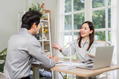 İş kadını bir toplantıda müşteriye ESG kavramlarını açıklar, sürdürülebilirliği ve kurumsal sorumluluğu vurgular.