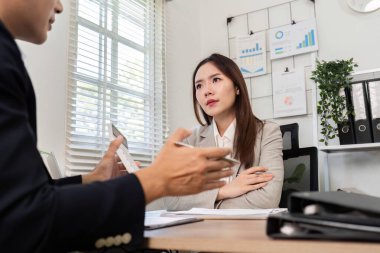 Odaklanmış bir mali danışman, modern bir ofis ortamında bir müşteriyle görüşlerini ve stratejilerini paylaşır..