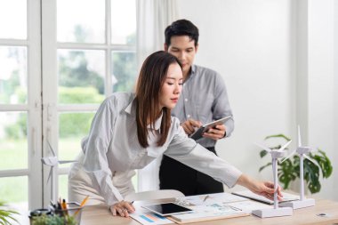 İş dünyasından profesyoneller, işbirlikçi bir ofis ortamında yenilenebilir enerji kavramlarını ve ESG girişimlerini aktif olarak analiz etmektedirler..