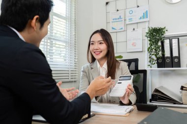 Neşeli bir finansal danışman, olumlu ve işbirlikçi bir atmosferi teşvik ederek, bir müşteriyle etkili stratejiler paylaşır..
