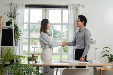 Parlak bir ofiste ESG girişimiyle başarılı işbirliklerini kutlayan iki iş adamı el sıkışıyor..