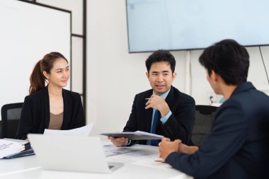 Bir grup profesyonel strateji tartışmalarına dalıyor, problem çözme becerilerini ve etkileşimli bir toplantıda başarıya olan bağlılıklarını sergiliyor.