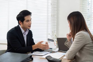 Finansal danışman, yatırım ve mali yetkilendirme stratejilerini tartışan verileri modern bir ofiste müşteriye sunar..