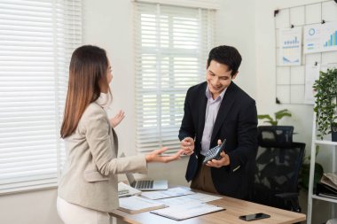 Bir kadın, bir erkekle tartışırken, parlak ve çağdaş bir çalışma alanında etkili bir iletişim ve takım çalışması sergiler..