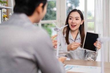 İş toplantısı sırasında tablet kullanarak sürdürülebilirlik fikirleri sunan bir kadın, iç içe geçen bir tartışmada ESG ilkelerini vurguladı.