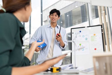 Genç bir mimar, ESG stratejileri ve sürdürülebilir uygulamaları tartışan modern bir ofiste bir meslektaşıyla görüşür..