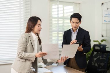 İki iş adamı stratejik bir tartışmaya giriştiler, proje belgelerini incelediler ve çağdaş bir ofis ortamında işbirliği yaptılar.