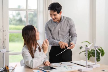 İki meslektaş, modern bir çalışma alanında yenilenebilir enerji modellerini incelerken ESG uygulamaları hakkında fikir ve görüşlerini paylaşıyor.