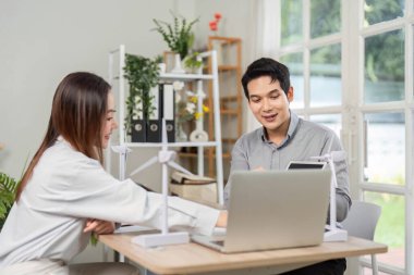 İki iş adamı, modern bir ofis ortamında yenilenebilir enerji çözümlerine odaklanarak ESG girişimleri hakkında bir tartışmaya giriştiler..