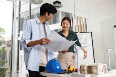 Planları inceleyen ve çağdaş bir çalışma alanında takım çalışmasını kutlayan iki mühendis. Yenilik ve işbirliği kavramı.