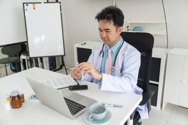 Hasta bakımına odaklanan doktor, tıbbi evrakları inceler ve hastalar için en iyi tavsiyeleri sağlamak için teknolojiyi kullanır..