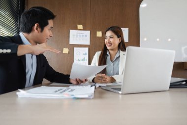 İşbirlikçi bir ofis ortamında, bir erkek ve kadın proje belgeleri, takım çalışmasının teşvik edilmesi ve yenilikler hakkında canlı bir tartışmaya girişirler..