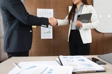 Bir kadın ve bir erkek, proje yönetimi görüşlerini tartıştıktan sonra profesyonel bir ortamda, anlaşma ve işbirliği anlamında el sıkışıyor..