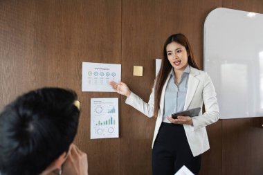 Etkileşimli bir oturumda, bir iş adamı proje yönetimi hakkında bir sunum yapar, içgörüleri etkili bir şekilde aktarır ve ekiple iletişim kurar..