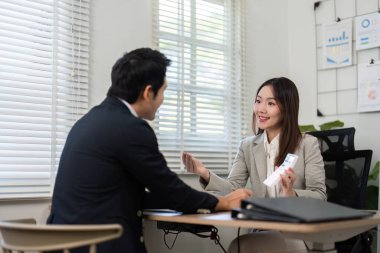 Bir finans danışmanı müşterisiyle görüşür, parlak bir ofis ortamında yatırım stratejilerini tartışır. Mali yetki ve danışmanlık hizmetleri kavramı.