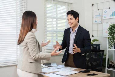 İki meslektaş proje stratejileri, parlak bir ofis ortamında takım çalışması ve işbirliği hakkında dinamik bir sohbete girişiyor.