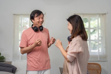 Oturma odalarında birlikte dans eden ve müzik dinleyen mutlu bir çift. Kulaklık takıp neşeli bağlarını kutluyorlar..