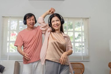 Yaşlı bir çift birlikte neşeli bir dans eder, kulaklık takar ve müziğin tadını çıkarırlar..