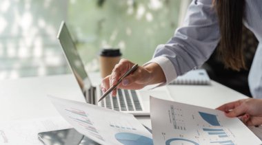 Profesyoneller, modern bir ofiste takım çalışması ve analitik düşüncenin altını çizerek, mali veriler ve raporlar hakkında ayrıntılı bir tartışmaya girişirler..