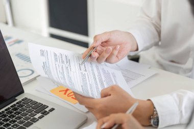 Bir birey, modern ofis ortamında mali detaylara odaklanarak vergi evraklarını ve hesaplamaları inceler..