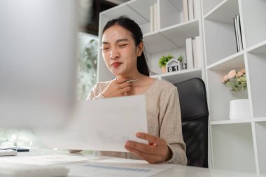 Modern bir ofiste belgeleri incelerken rahatsızlık duyan bir kadın ofis sendromunun etkilerini vurguluyor..