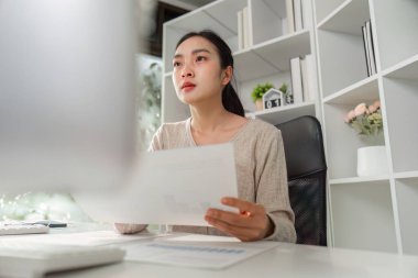 Bir ofis çalışanı dikkatle mali raporlara bakar, odaklanmayı ve işle ilgili stresi yönetme zorluklarını yansıtır..