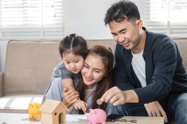 Bir aile, kumbara ve hesap makinesi kullanarak finansal planlamada işbirliği yapıyor, çocuklara para biriktirmenin değerini öğretiyor..