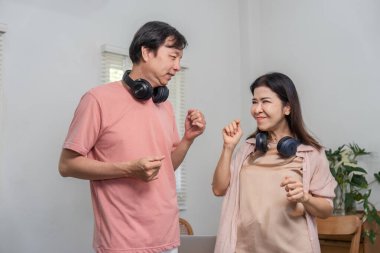 Orta yaşlı, neşeli bir çift oturma odalarında kulaklık takıp dans ediyor ve müzikle eğleniyorlar. Sıcak bir ortamda neşeli bir anı kucaklıyorlar..