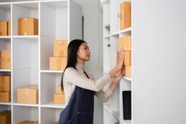 Genç bir kadın, girişimci ruhunu ve işine bağlılığını yansıtan, modern ofis ortamında kutular düzenler..