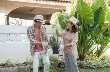 Çeşitli çiftler birlikte bahçıvanlık yapıyor, bir saksı çiçeği tutuyor ve yemyeşil arka bahçelerinde gülümsüyor, ortak bir hobiyi kucaklıyorlar..